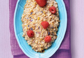 Auf dem Foto ist eine blaue Schale auf violettem Hintergrund zu sehen. In der Schale ist Flower Power Risotto mit Erdbeeren und Himbeeren zu sehen. | © SONNENTOR