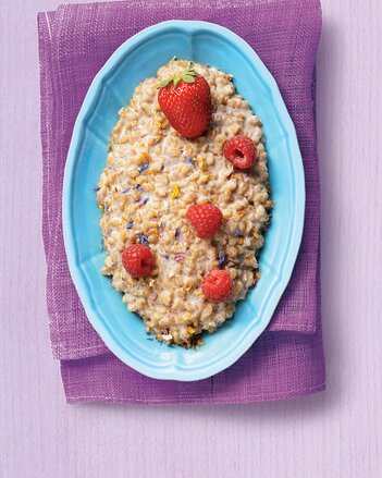 Auf dem Foto ist eine blaue Schale auf violettem Hintergrund zu sehen. In der Schale ist Flower Power Risotto mit Erdbeeren und Himbeeren zu sehen. | © SONNENTOR