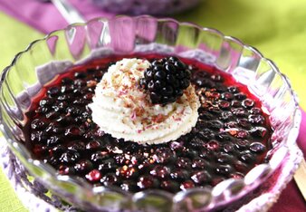 Foto von einem Schälchen mit Beeren-Gewürzgelee. Auf dem dunkelroten Gelee ist ein weißes Obers Tüpfelchen und eine Brombeere zu sehen. | © SONNENTOR