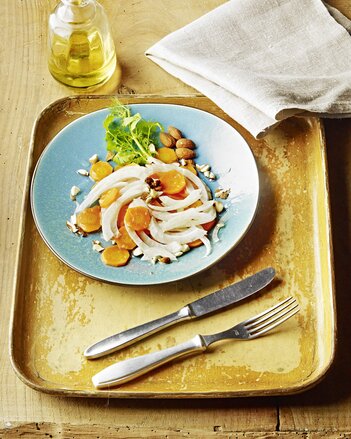 Auf dem Foto ist ein Teller mit Karotten-Fenchel-Salat zu sehen. Dahinter sieht man ein kleines Fläschchen Öl. | © SONNENTOR