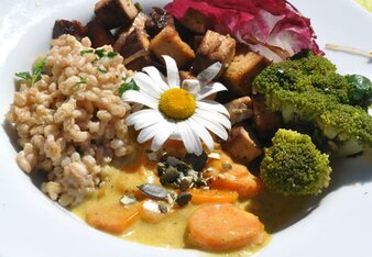 Auf dem Foto ist ein Teller mit Tofu, Kürbiskernen, Brokkoli und Karotten zu sehen. Darauf ist eine Blume zu sehen. | © SONNENTOR