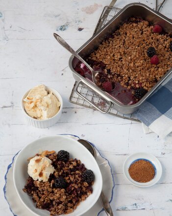 Auf dem Foto ist eine Schale mit Beeren Crumble zu sehen. Dahinter sieht man eine Backform ebenfalls mit Beeren Crumble. | © SONNENTOR