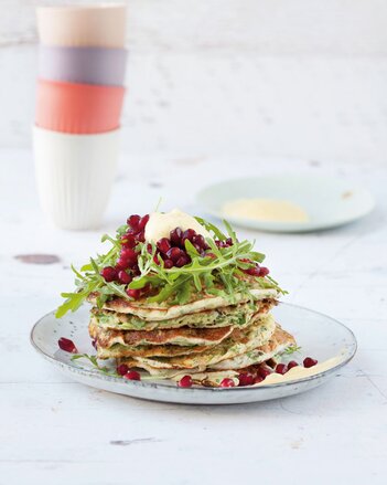 Auf dem Foto ist ein Turm von Rucola-Pancakes zu sehen. Darauf sind frischer Rucola und Granatapfelkerne zu sehen. | © SONNENTOR