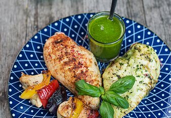 Auf dem Foto sind zwei Hühnerbrustfilets und ein Hühnerspieß zu sehen. Daneben steht ein Gläschen mit Salsa Verde. | © SONNENTOR