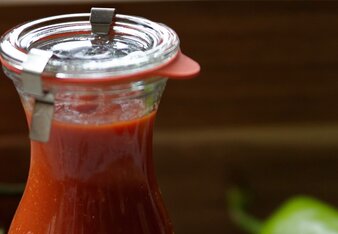 Auf dem Foto ist ein Glas gefüllt mit Gute Laune Ketchup zu sehen. Daneben liegen Tomaten. | © SONNENTOR