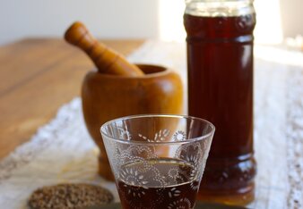 Auf dem Foto sieht man ein Shotglas mit Kräuterlikör. Dahinter sieht man eine Flasche voll mit Kräuterlikör. | © SONNENTOR