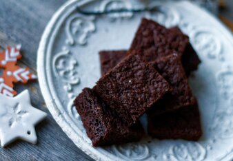 Auf dem Foto ist ein weißer Teller mit Lebkuchen Brownies zu sehen. Davor liegt eine Packung SONNENTOR Lebkuchengewürz. | © SONNENTOR