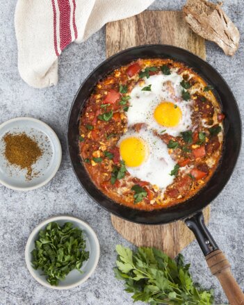 Auf dem Foto ist eine Pfanne mit Shakshuka zu sehen. Sie ist mit frischer Petersilie bestreut. | © SONNENTOR