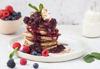 Auf dem Foto sieht man einen Stapel mit Pancakes. Sie sind mit verschiedensten Früchten garniert. | © SONNENTOR