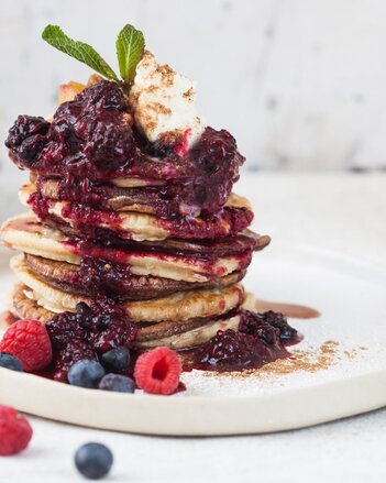 Auf dem Foto sieht man einen Stapel mit Pancakes. Sie sind mit verschiedensten Früchten garniert. | © SONNENTOR