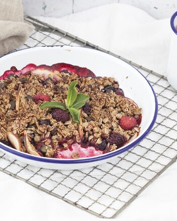 Auf dem Foto ist ein Beeren-Frühstücks-Crumble zu sehen. Daneben steht eine Tasse Tee. | © SONNENTOR