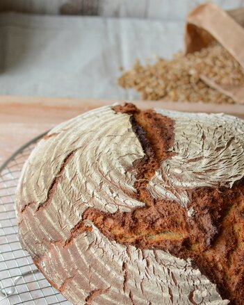 Auf dem Foto ist ein Laib klassisches Bauernbrot zu sehen, das auf einem Gitter liegt. | © SONNENTOR