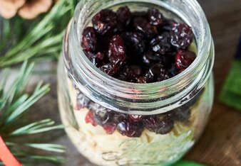 Auf dem Foto ist ein Glas mit Porridgemischung zu sehen. Daneben liegen eine Sonnentorteepackung, Zapfen und Tannenzweige. | © SONNENTOR