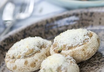 Auf dem Foto sind drei Stück gefüllte Pilze zu sehen. Sie sind mit Parmesan bestreut. | © SONNENTOR