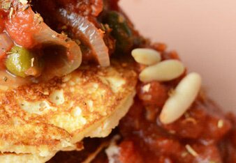 Auf dem Foto sieht man würzige Pancakes mit Tomaten-Kapern-Ragout darüber. | © SONNENTOR