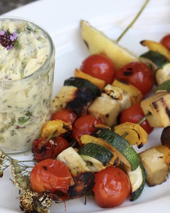 Auf dem Foto sieht man mehrere Grillspieße. Daneben steht ein Glas mit Dip. | © SONNENTOR