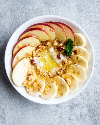 Auf dem Foto ist eine Schüssel mit Basenmüsli zu sehen. Darauf sind viele Toppings wie Bananen, Äpfel und Nüsse zu sehen. | © SONNENTOR