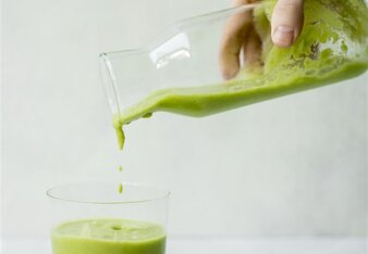 Auf dem Foto ist zu sehen wie aus einer Karaffe ein grüner Smoothie in ein Glas gefüllt wird. | © SONNENTOR