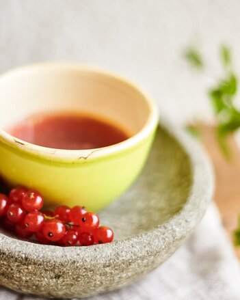 Auf dem Foto ist eine Schale mit Preiselbeerddressing zu sehen. Davor liegen frische Preiselbeeren. | © SONNENTOR