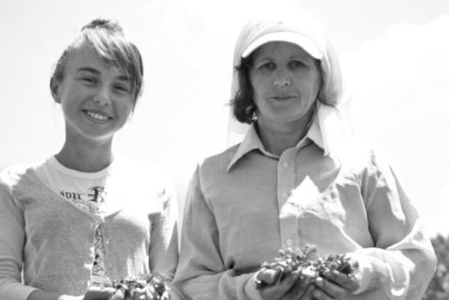 Black and white photo of a child and a woman holding herbs in their hands. | © SONNENTOR