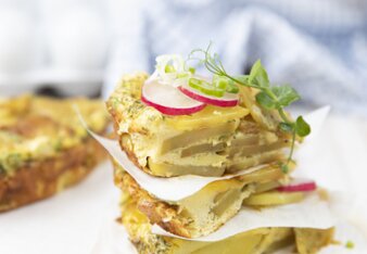 Auf dem Foto sieht man einen Turm aus Tortillas de Patatas. Sie sind mit Radieschen, Jungzwiebel und Sprossen garniert. | © SONNENTOR