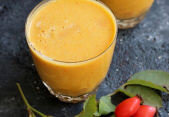 Au dem Foto sind zwei Gläser mit Hagebutten Smoothie zu sehen. Daneben sind frische Hagebutten zu sehen. | © SONNENTOR