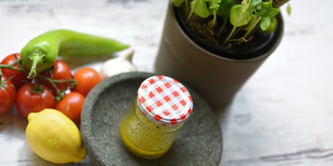 Auf dem Foto sieht man ein Glas mit Dressing. Daneben liegen Paprika, Tomaten und eine Zitrone. | © SONNENTOR