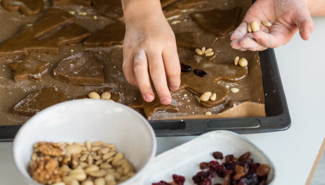 Auf dem Foto sieht man wie ein Kind ein Lebkuchenmännchen dekoriert. | © SONNENTOR