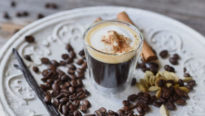 Auf dem Foto ist ein Espresso zu sehen. Daneben liegen Kaffeebohnen, Zimtstangen und Vanilleschoten. | © SONNENTOR