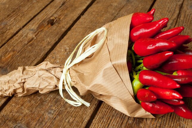 Auf dem Foto sieht man einen Strauß aus Chili. Er ist wie ein Blumenstrauß mit Papier umhüllt. | © SONNENTOR